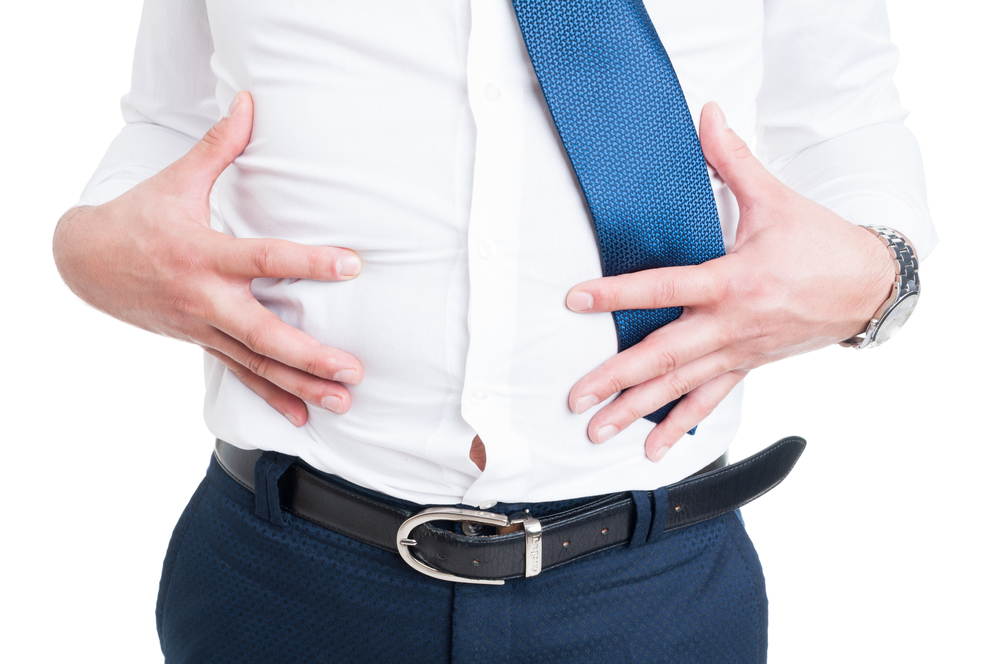 Businessman in closeup holds his stomach because of bloating